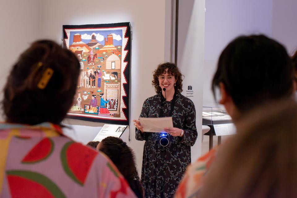 educator standing in front of three students talking about weaving behind her