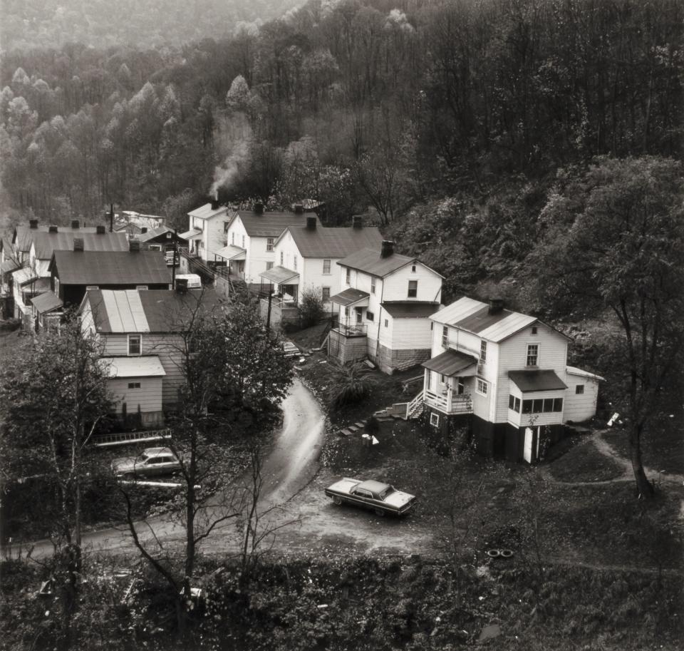 Exhibition - Much Here is Beautiful, Former Company Houses Black and white photograph of a row of houses seen from a distance.