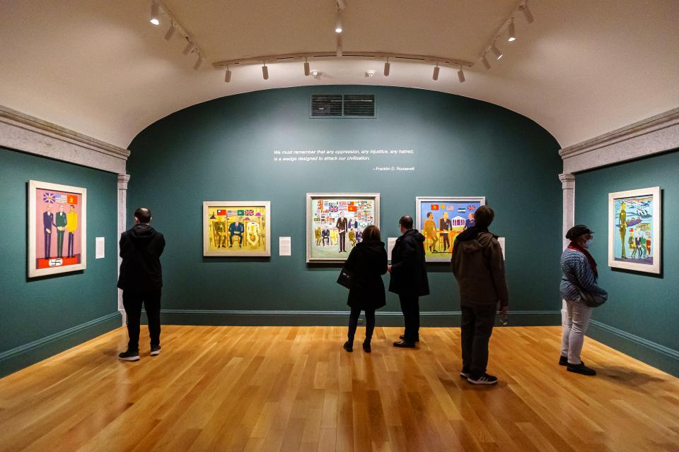 Visitors looking at William H. Johnson paintings on a wall.