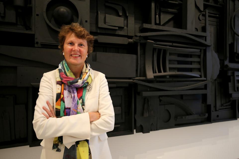 A photograph of a woman standing next to an artwork