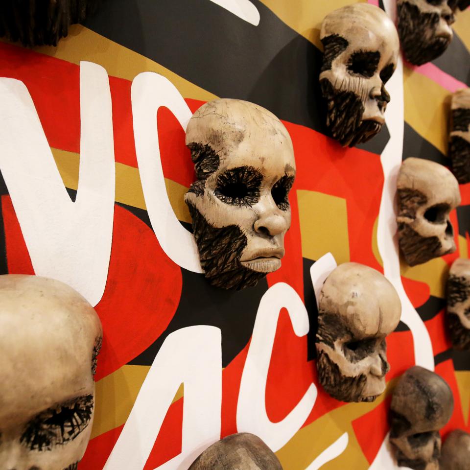 A detailed photograph of wood carved skulls on a wall.