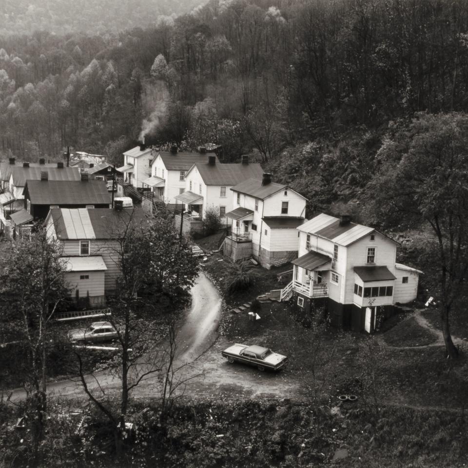 Black and white photograph of a row of houses seen from a distance.