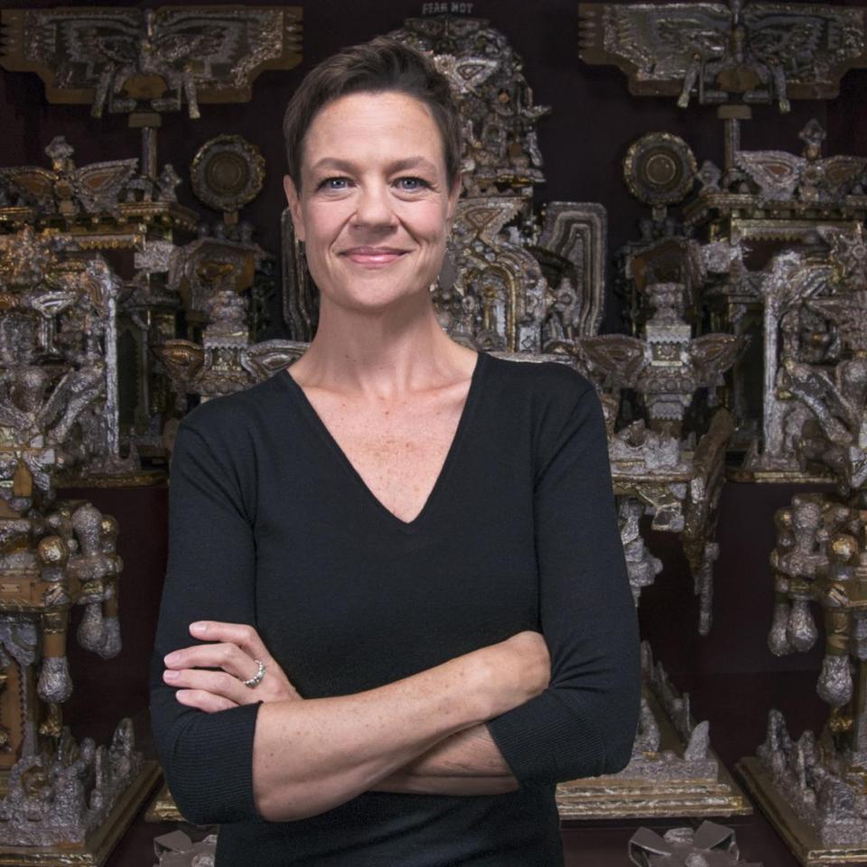 A photograph of a woman standing in front of artwork.