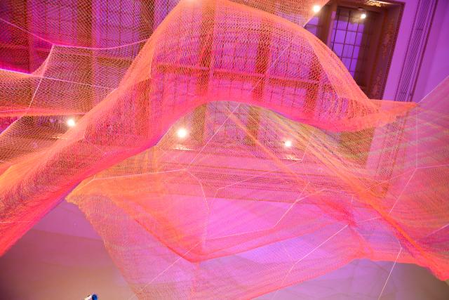 A photograph of colorful mesh hung from the ceiling inside the Grand Salon at the Renwick Gallery.