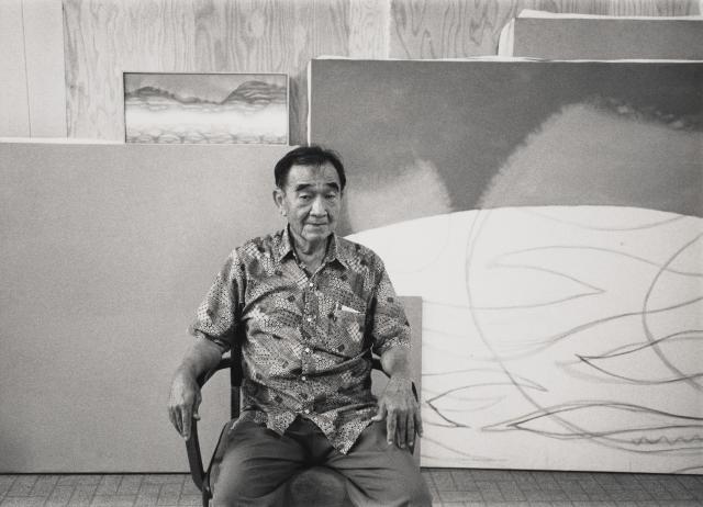 saam-2024.52.41.15_1.jpg photo of person sitting in chair infront of art leaning on a wall