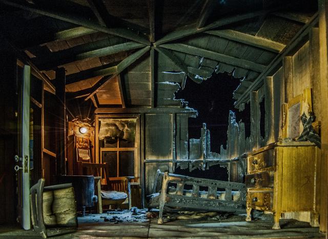 A photograph of a nutshell study of unexplained death showing a detail of a burned cabin.