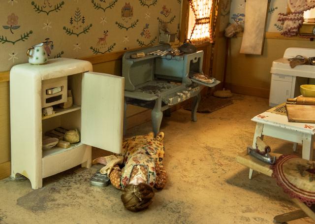 A photograph of a nutshell study of unexplained death showing a detail of a woman's death inside a kitchen.