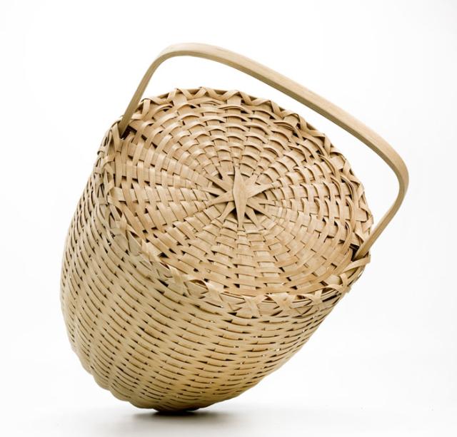 A basket with an oval shape and a lid and handle. 