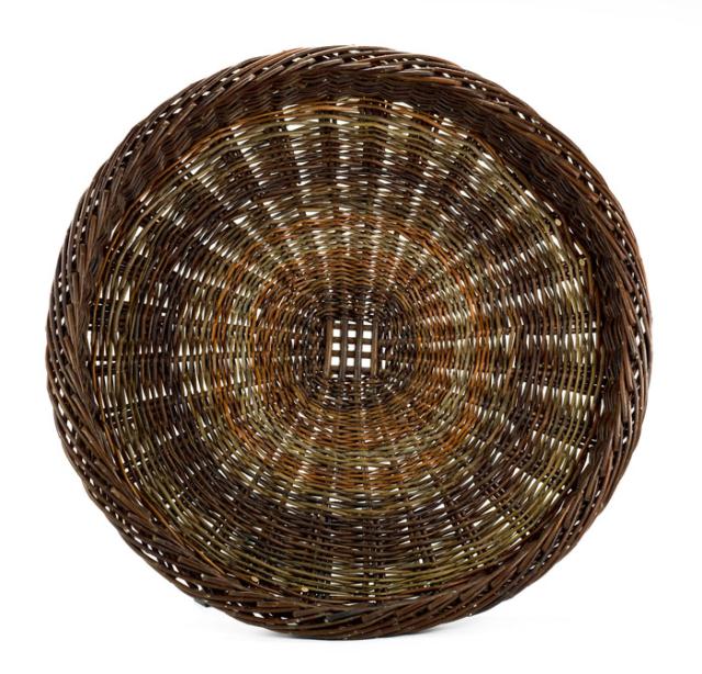 A basket that is the shape of a large plate with a multicolored design.