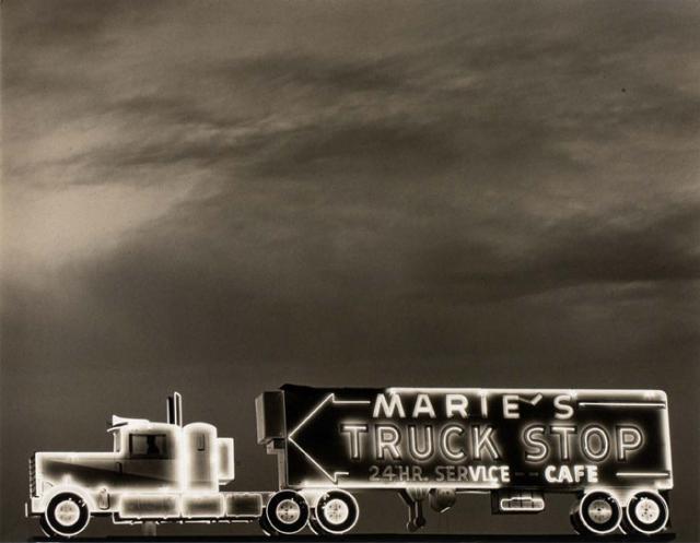 A photograph of a truck stop with a highway sign in Arizona.
