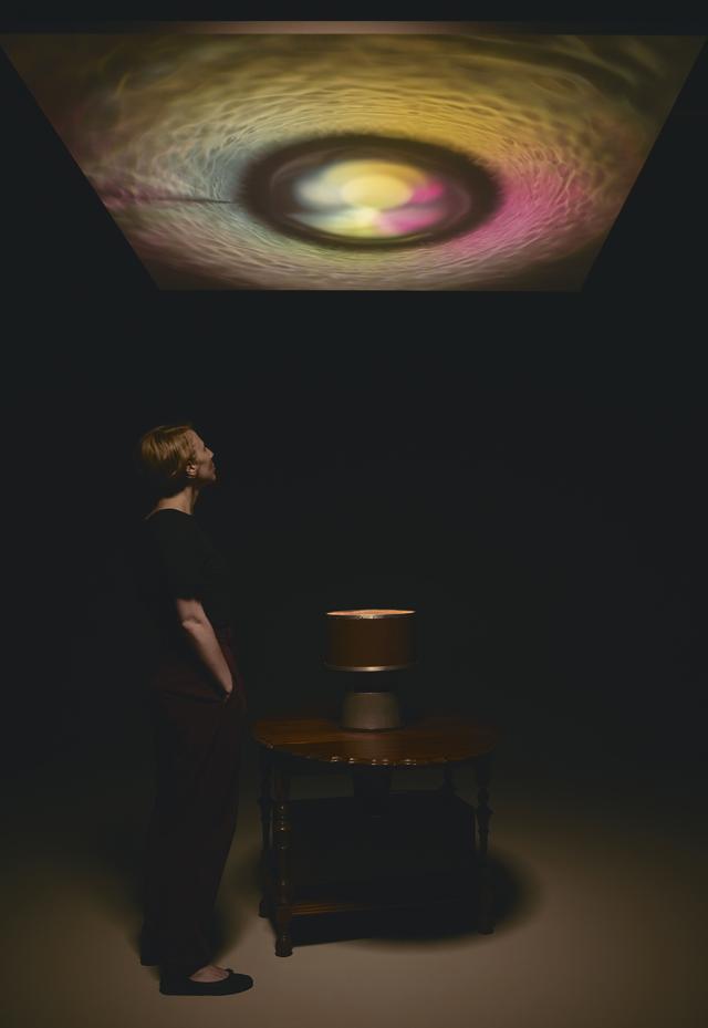 A light study in a room with a person looking at it made with yellow, pink, and green tones.