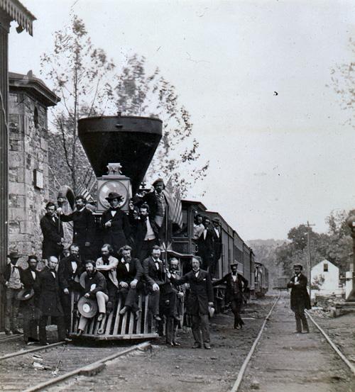 A salt paper print of men posing with a railroad car. 