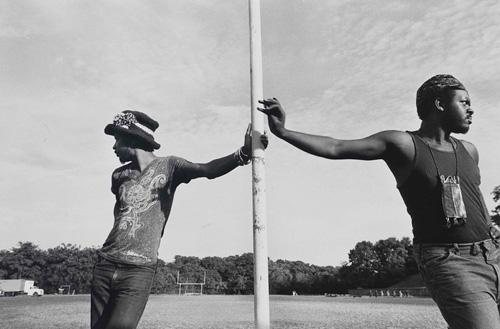Freeman's gelatin silver print of two men leaning against the same pole. 