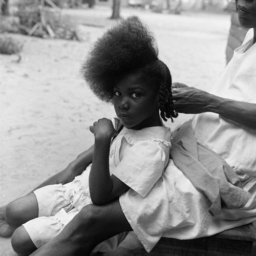 Gleaton's gelatin silver print of a young girl getting her hair done.