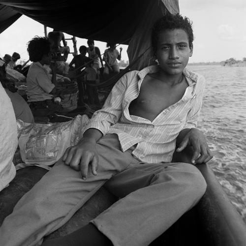 Gleaton's gelatin silver print of a boy in a boat looking at the camera.