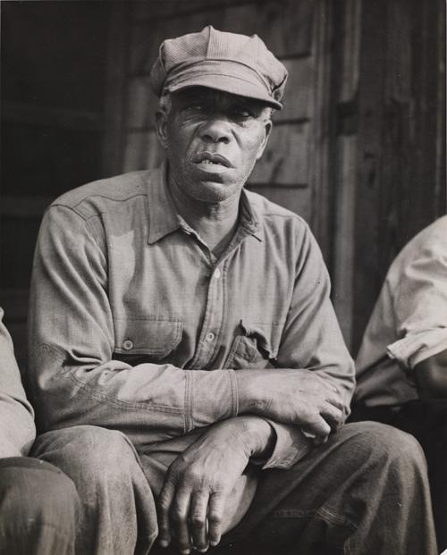McNeill's gelatin silver print of a man sitting down.