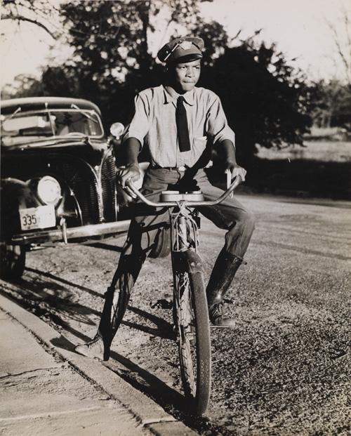 McNeill's gelatin silver print of a boy riding a bike.