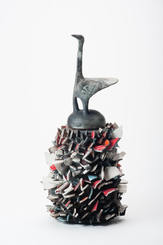 A sculpture of a ceremonial vessel with a bird on top.