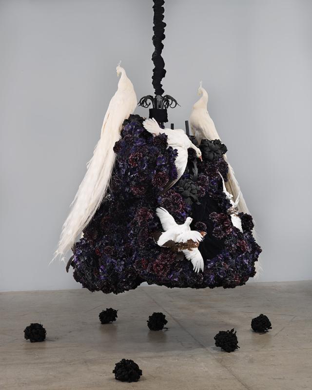 A photograph of a large black object hanging and white birds resting on it.