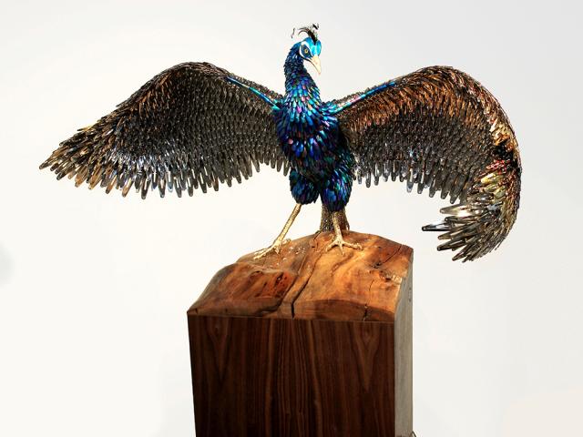 A mixed media bird with its wings spread out.