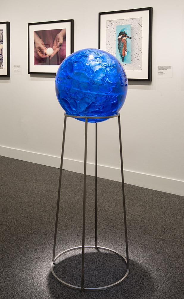 A blue circular crystal on a metal stand. 
