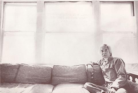 A photograph of a man sitting on a couch.