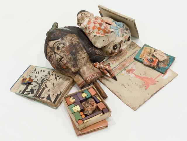 An assortment of toys and books made of wood, and unfired clay.