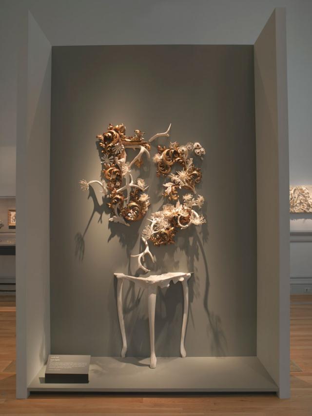 An in gallery photograph of objects on a wall above the side of a table.