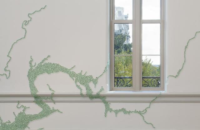 A photograph of marbles in an organic form on a white wall.