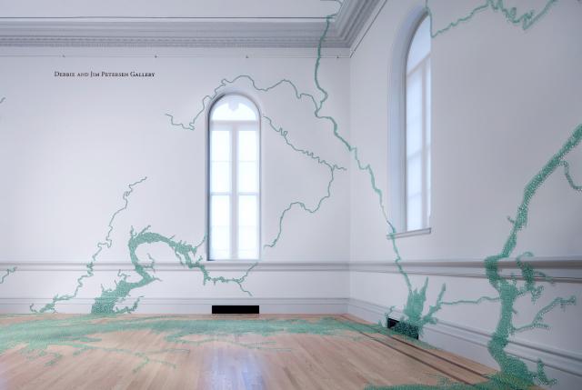 A photograph of marbles in an organic form on a white wall.