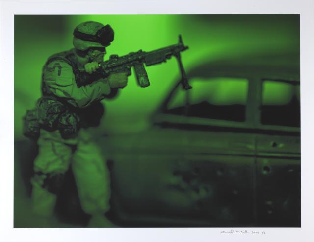 A photograph in green of a man with a gun.