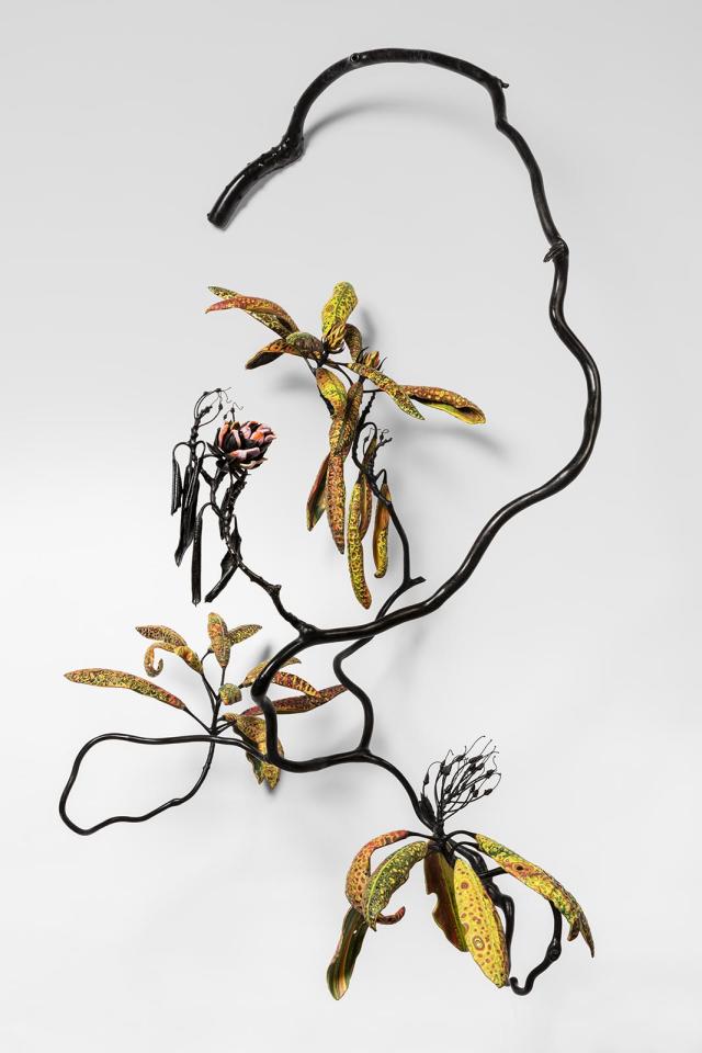 A piece of a plant with a branch, and yellow, green, and orange flowers.