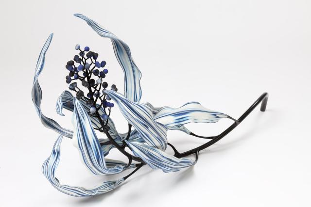 An artwork made to look like a flower with blue and white leaves and small dark circles on the inside. 