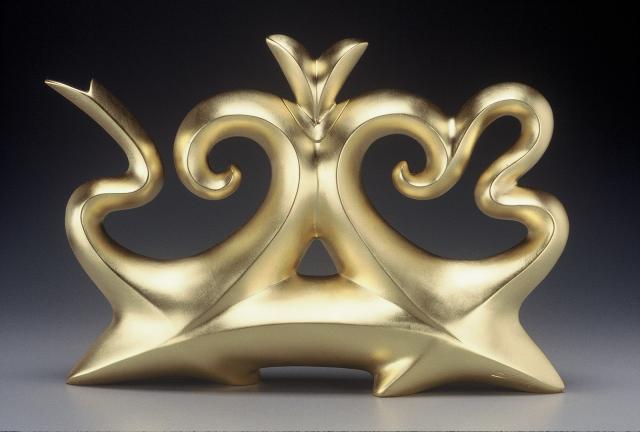 A gold abstract tea pot with circular forms.
