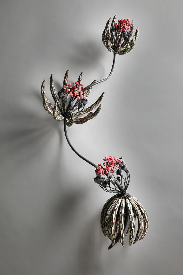 An artwork of a plant with three flowers with pedals and small pink centers.