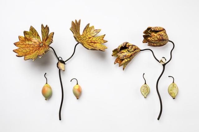 Two flowers made of porcelain with two yellow leaves on each.