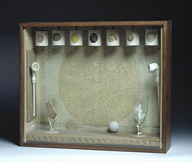 A box with seven things hanging from the top and a glass inside. 