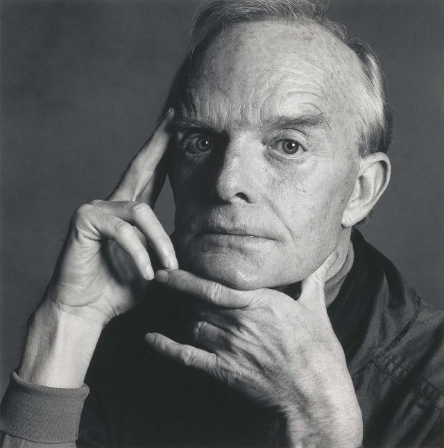 A detailed photograph of a man's face with his hands in the frame.