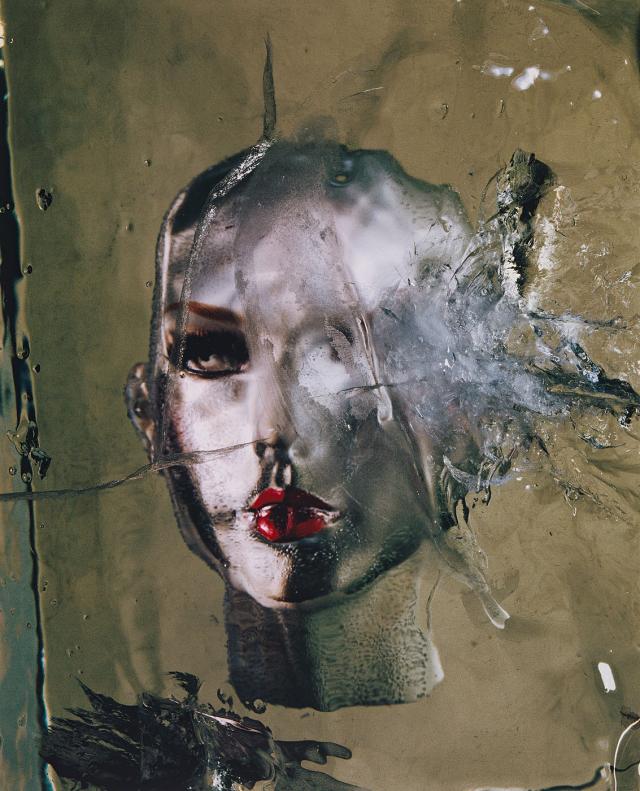 A photograph of a mannequin head frozen in ice.