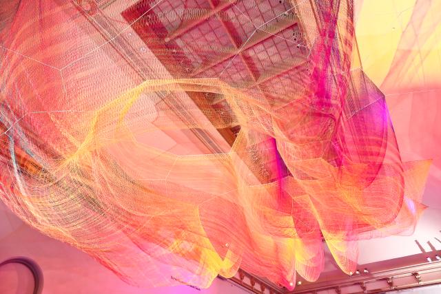 A photograph of colorful mesh hung from the ceiling inside the Grand Salon at the Renwick Gallery.