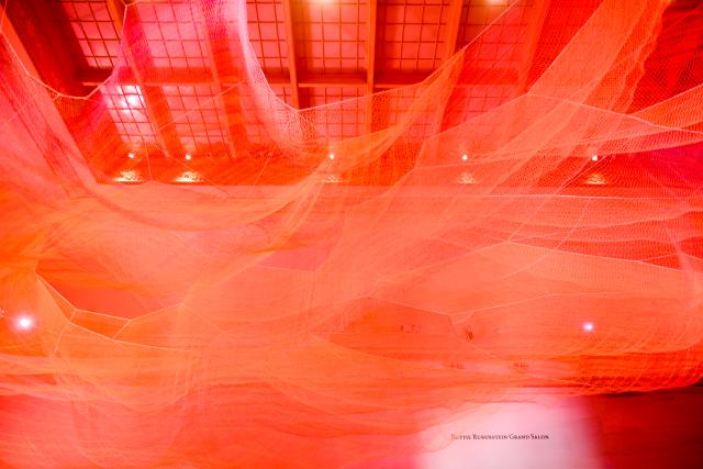 A photograph of colorful mesh hung from the ceiling inside the Grand Salon at the Renwick Gallery.