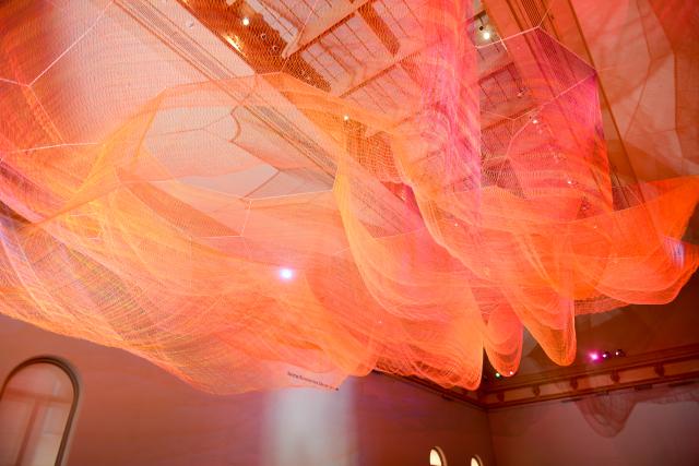 A photograph of colorful mesh hung from the ceiling inside the Grand Salon at the Renwick Gallery.