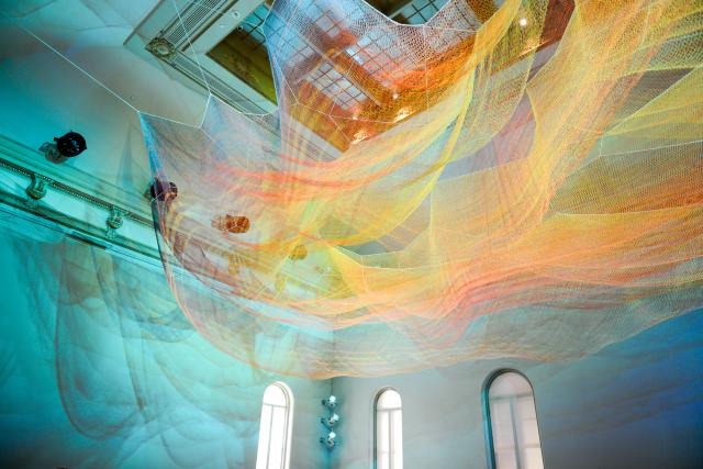A photograph of colorful mesh hung from the ceiling inside the Grand Salon at the Renwick Gallery.