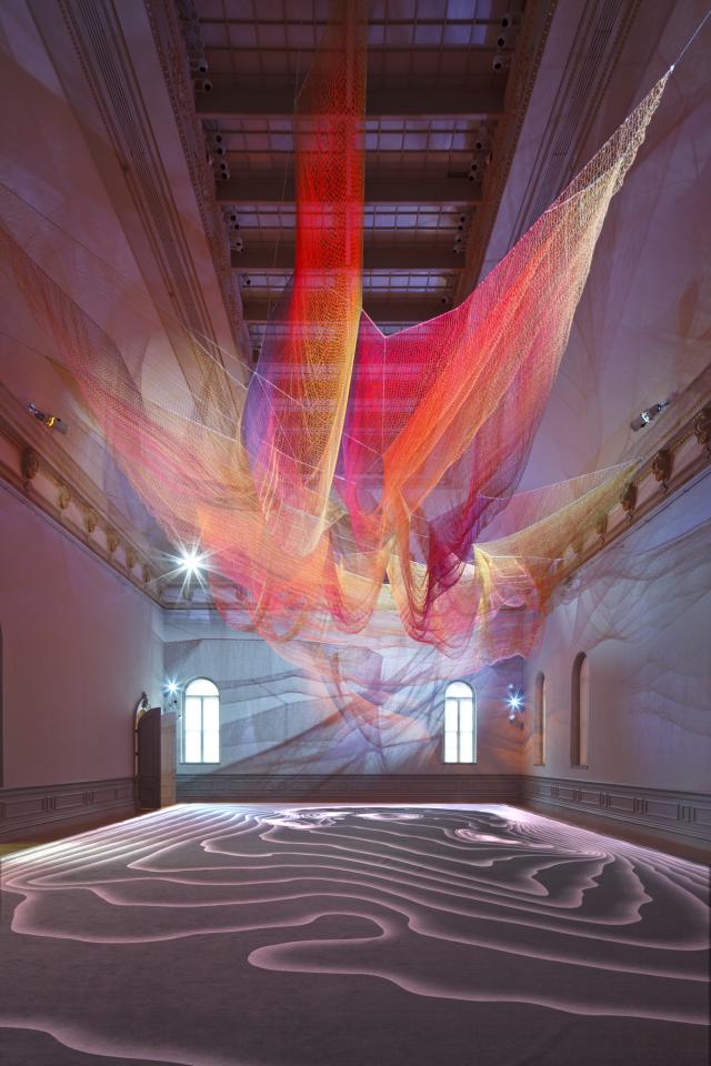 A photograph of colorful mesh hung from the ceiling inside the Grand Salon at the Renwick Gallery.