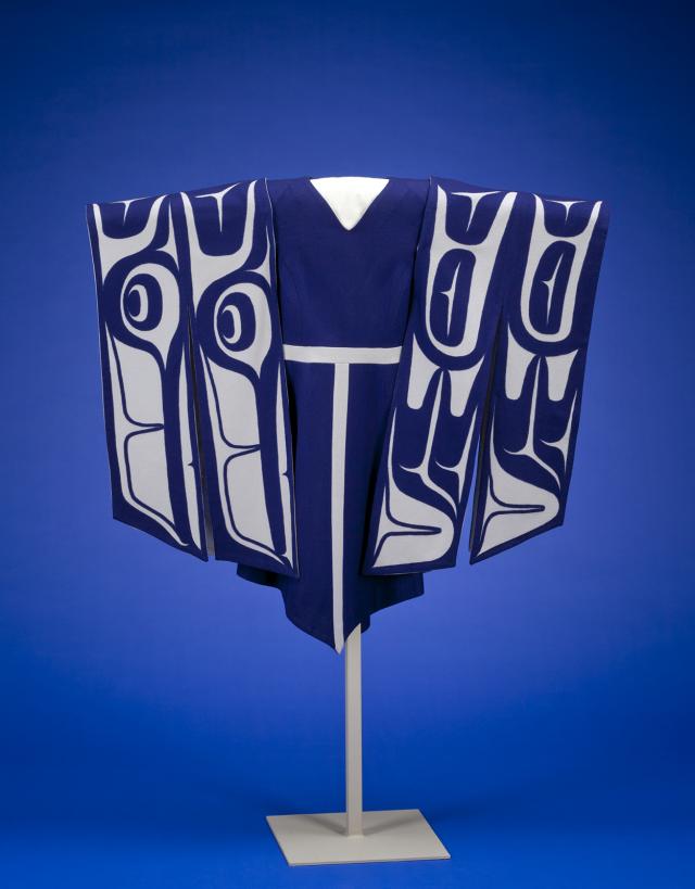 A blue dress handing on a stand with sleeves made of white and blue material depicting wings.