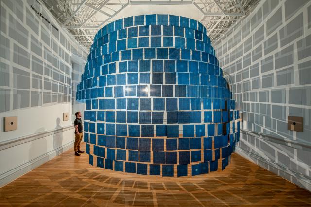 An installation view of small indigo cloths hanging from the ceiling