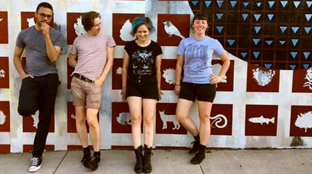 the four musicians of Bad Moves pose against a wall mural