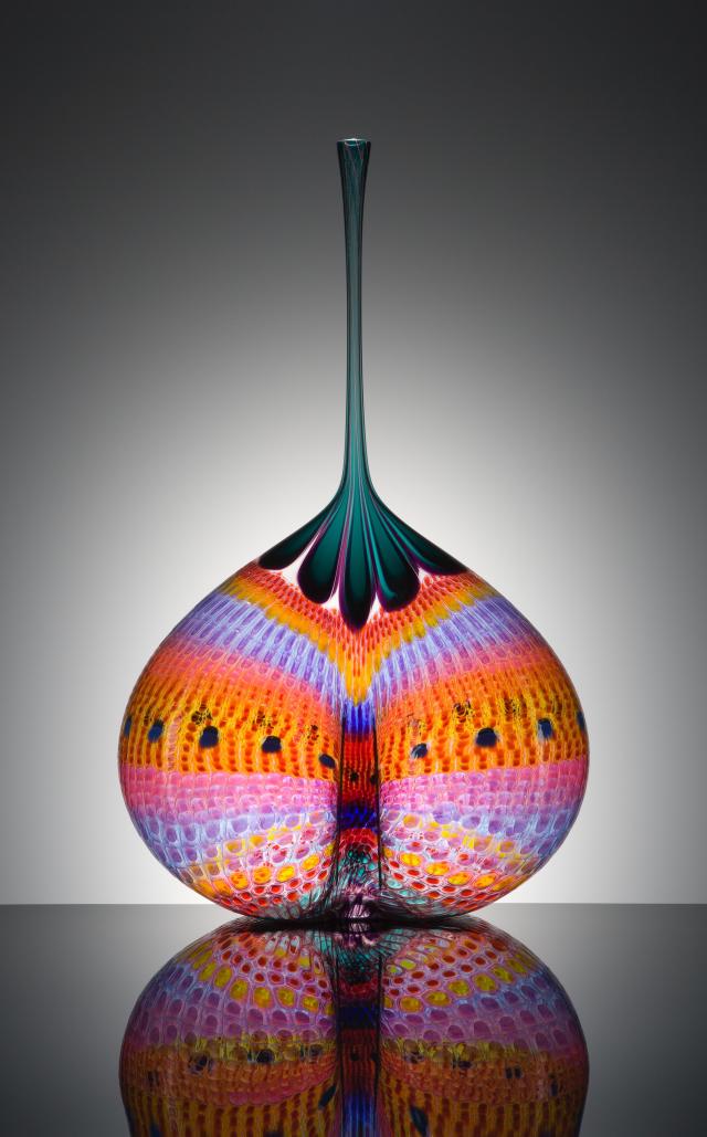 blown glass object with orange pink and blue tie dye design