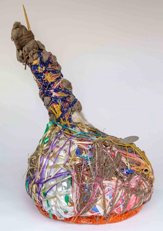 A sculpture in the shape of a bottle with wrapped pieces of string.