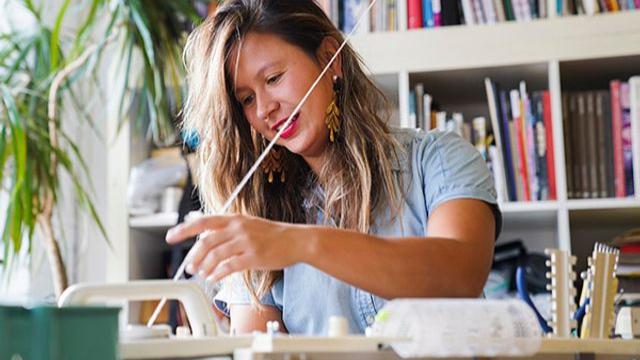 Maggie Thompson sits at a table making artwork